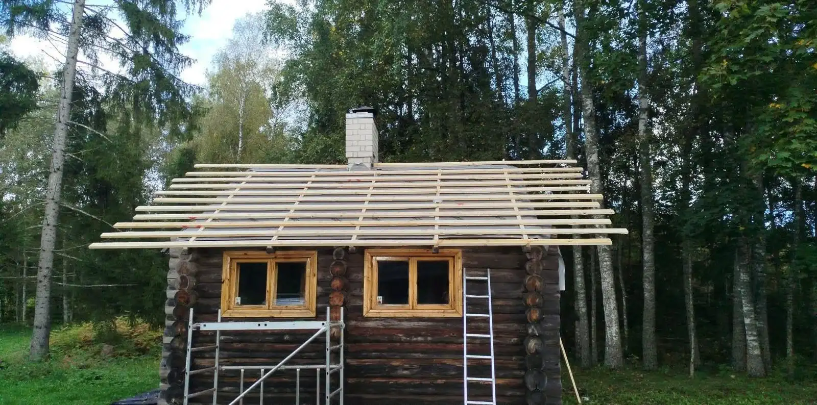 Old roof stripped, rafters and chimney exposed, scaffolding alongside