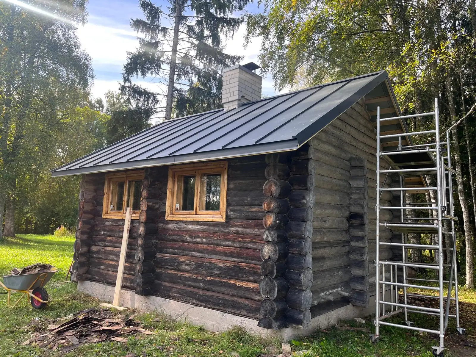 Log sauna with a new dark standing-seam metal roof
