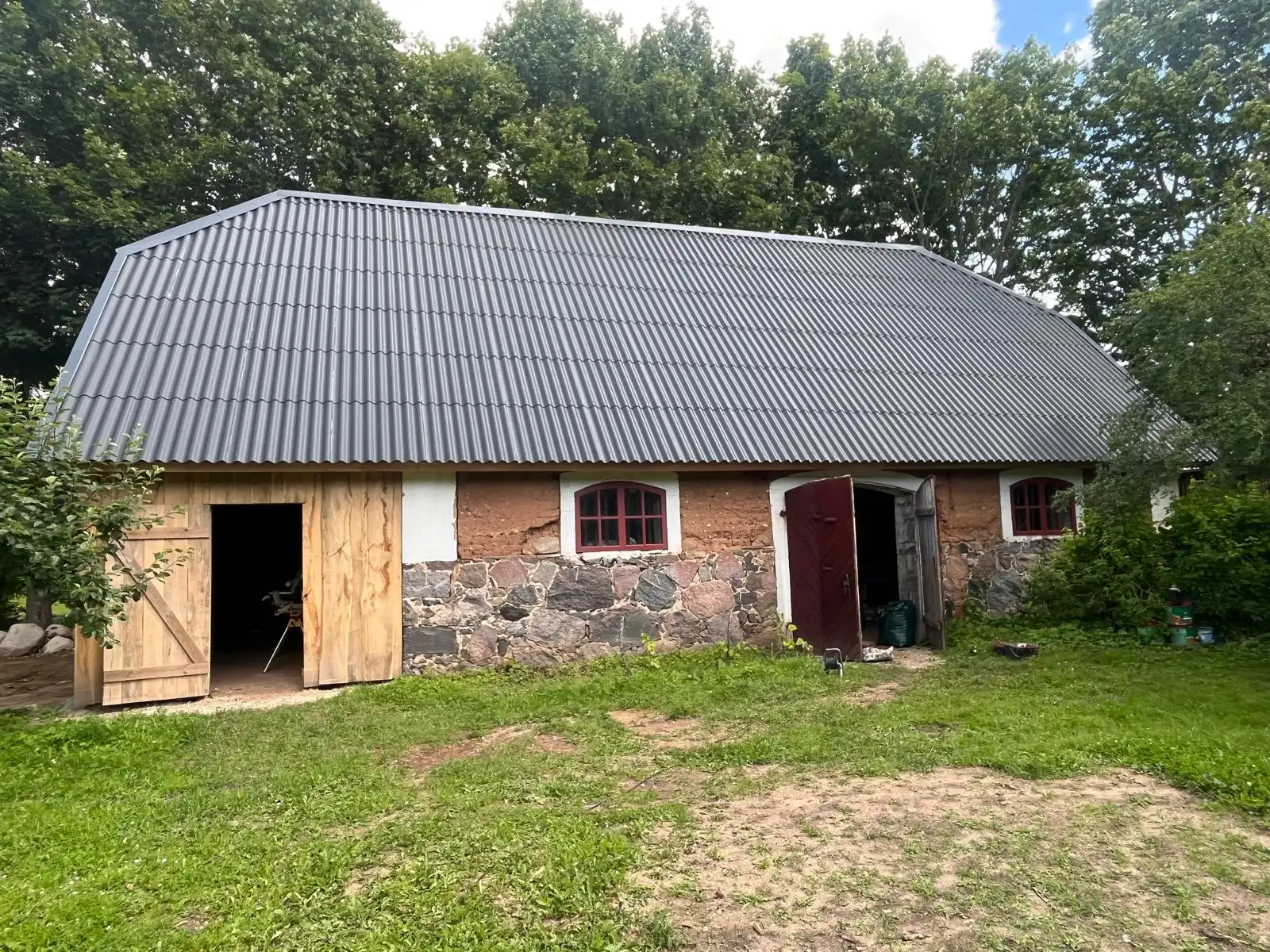 Clay-walled building with a new metal roof and red arched windows